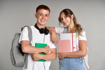 Portrait of caucasian teenage girl and boy holding school books and wearing schoolbags