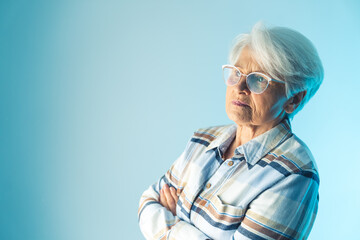 Elderly retired short-haired woman looking away thoughtfully with her arms crossed and reflecting on memories or thinking about something. High quality photo