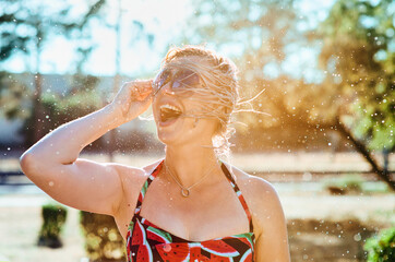 laughing emotional blonde woman with wet hair making water splashes. Holidays, happiness, fun, summer, leisure concept