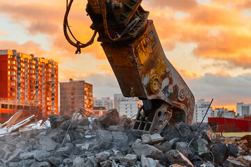 Concrete crusher works with pile of cement stones closeup