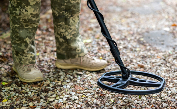 A military sapper with a metal detector in the field. A Ukrainian explosive technician carries out demining work. 