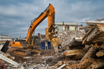 Fototapeta premium Excavator destroyer with hydraulic scissors cuts concrete