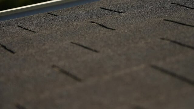 Texture of shingles. Focus slides back and force over surface of grey protective material covering top of attic roof. Closeup view 4k video footage of part of gray shingled roof of countryside house