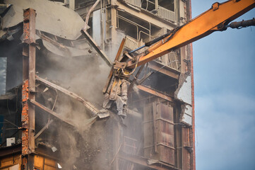 Hydraulic cutter of crane demolishes old industrial building