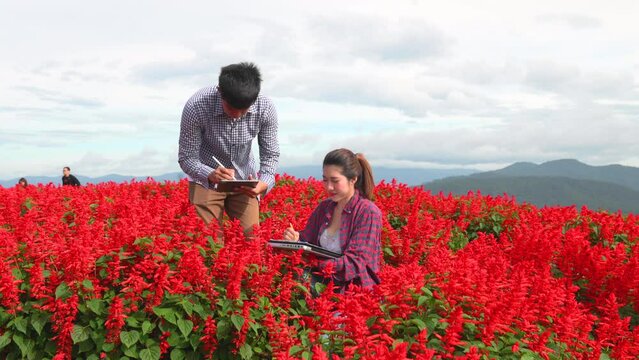Co working farmer discussion and using technology digital tablet walking through flowerr field inspect for quality control, Agro-Industry concept.