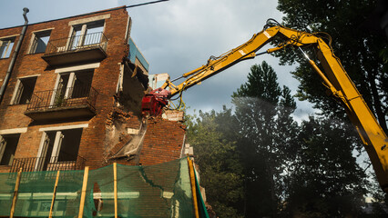 Demolition of a brick building with excavator mechanical arm. Destruction of dilapidated housing....