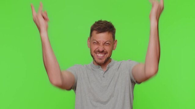 Overjoyed delighted handsome man showing rock n roll gesture by hands, cool sign, shouting yeah with crazy expression, dancing, emotionally rejoicing in success. Adult guy on chroma key background