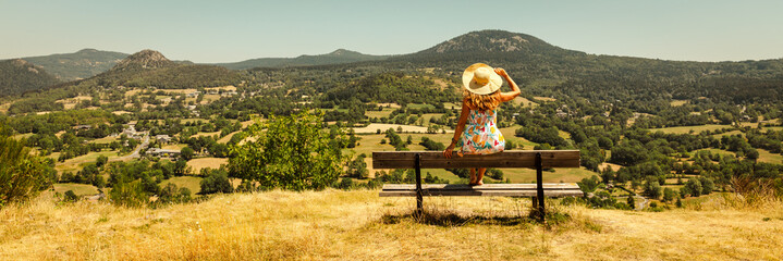woman on a bench looking at Auvergne landscape panorama- volcano suc