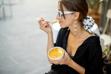 Woman eating dessert with creme brulee at the restaurant outdoors. Concept of italian cuisine