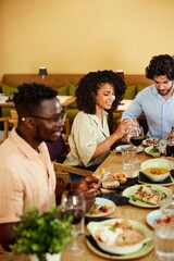 A group of multicultural friends eats dinner at the restaurant.