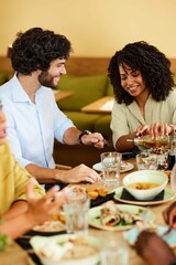 A group of multicultural friends eats dinner at the restaurant.