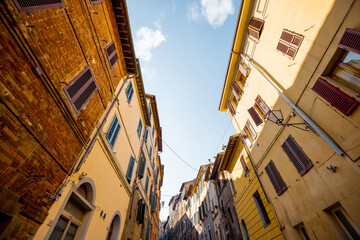 Fototapeta premium View on narrow and cozy street in the old town of Siena city in Italy. Concept of ancient architecture of the Tuscan region