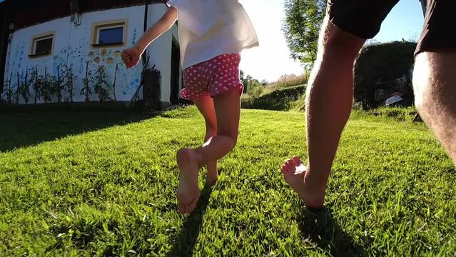 Young Girl Running Barefoot with Father on Farm Grass at Sunset Slow Motion