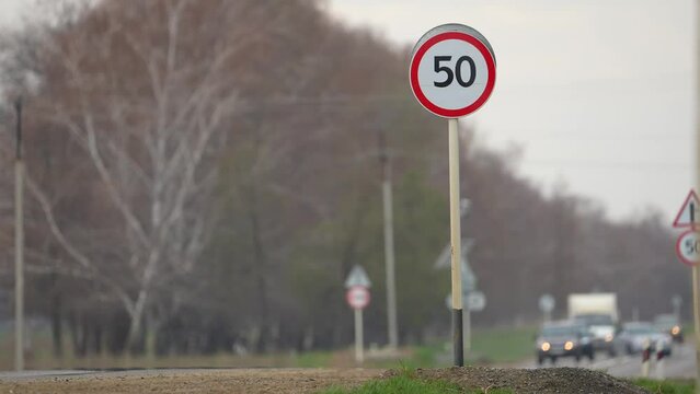 50 km per hour sign. Cars moving along the highway next to a 50kmh speed limit sign. Danger part of the road.