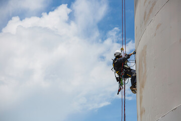 Male worker down height tank roof rope access safety inspection thickness weld of storage tank gas