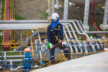 Male worker inspection wearing safety first harness rope safety line working at a high place on tank roof spherical gas