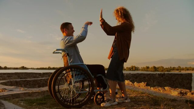 Young man in a wheelchair in the company of friends playing lawn games. The disabled man lives an ordinary life.The girl and the disabled guy spend time together on the beach