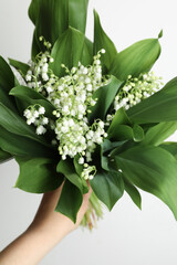 Woman holding lily of the valley flowers on white background, closeup