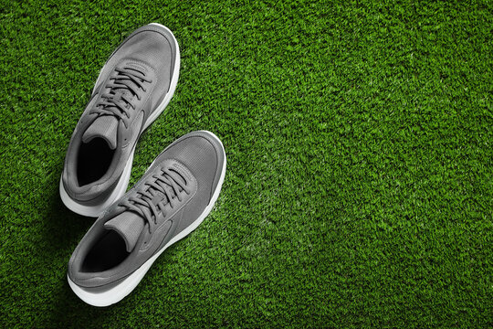 Pair of stylish sport shoes on green grass, flat lay. Space for text