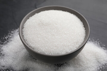 Granulated sugar on black table, closeup view