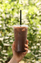 Woman holding takeaway plastic cup with cold coffee drink outdoors, closeup