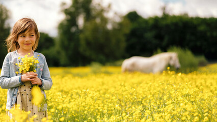 Naklejka na ściany i meble A little girl is standing in a field with yellow flowers, holding a bouquet of wildflowers, a white horse is grazing in the field, the concept of peace, no war, peaceful sky, Ukraine