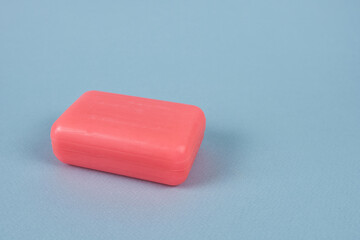 A piece of pink soap on a blue background, close-up. Detergent.