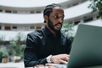 Young businessman working on his laptop in a hall of a condo