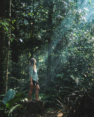Naklejka na ściany i meble Mulher iluminada por raio de luz entre árvores da floresfa no Parque nacional montanhas do tumucumaque, amapá.