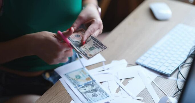 A woman cuts out fake dollars with scissors, close-up