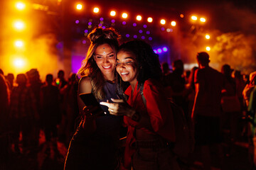 Female friends using cellphone at music festival