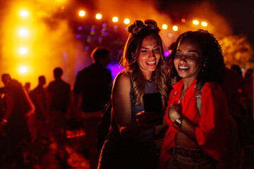 Two female friends using cellphone at music festival