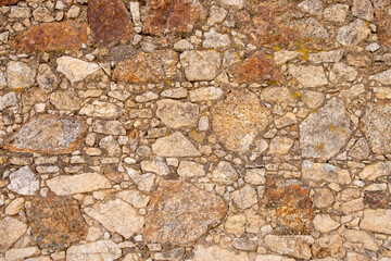 A wall built with granite stones and joined with cement.