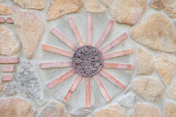 A wall of granite stones decorated with geometric figures of bricks.