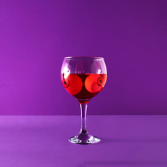 Copa glass for gin cocktails, red drink and funny eye balls in it. Creative Halloween party inspired layout against purple background. 