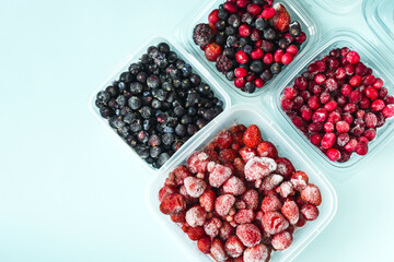Frozen strawberries blackberries cranberries and blueberries with ice crystals on a light background top view