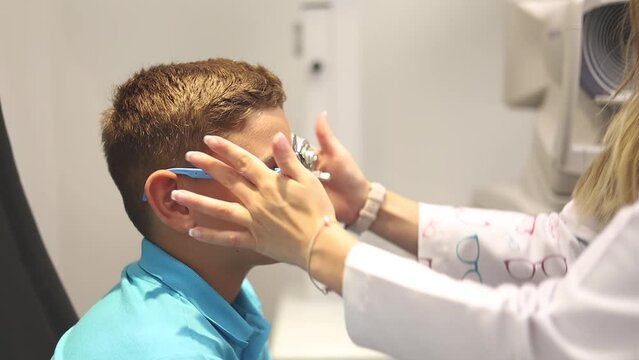 A female ophthalmologist fits a child with trial glasses for an eye test.