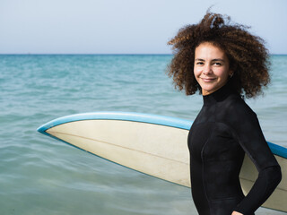 Portrait of a multiracial young surfer woman getting into the water