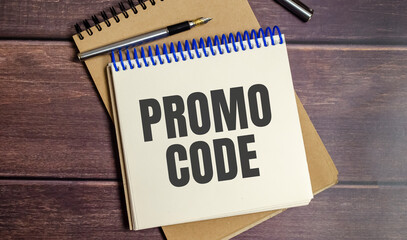 word promo code on notepad and wooden background