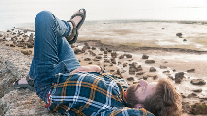 Hombre blanco barbudo pelirrojo tumbado en una playa en marea baja