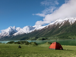 Red tent and snow-capped green mountains