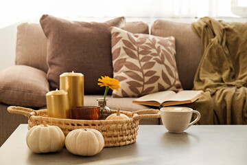 Fototapeta na wymiar Bunch of pumpkins of different kinds, shapes and colors on the floor and a table, open book and cup of coffee. Symbol of autumnal holidays with a lot of copy space for text, close up, background.