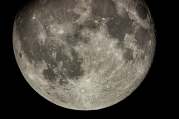 Details of the full moon photographed by a telescope, craters and mountains are visible far away.
