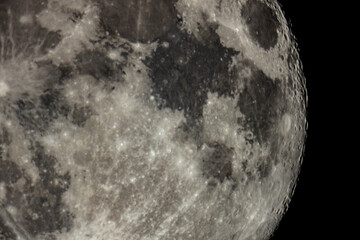Details of the full moon photographed by a telescope, craters and mountains are visible far away.