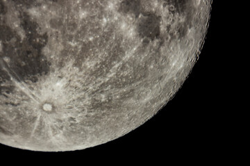 Details of the full moon photographed by a telescope, craters and mountains are visible far away.