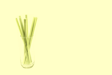 Bamboo straws in a glass against light yellow background