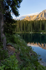 Splendid view of Lake Carezza in South Tyrol. The mountains and the forest are perfectly reflected on the lake, a suggestive image. A dream place for a relaxing holiday in nature.