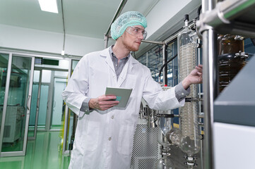 Inspector caucasian scientists are in the machine room extracting oil and cannabis seeds	