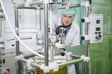 Inspector caucasian scientists are in the machine room extracting oil and cannabis seeds	