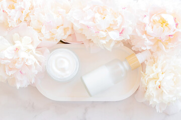 Fototapeta na wymiar Face and eye moisturizer cream and serum in a glass bottle and jar and peony flowers on light marble background. Concept eco organic natural cosmetic products for skincare